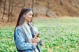 Woman enjoying spring day at nature. Lifestyle, people and spring time. Young woman with book on the walk