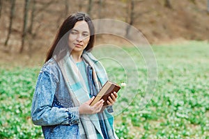 Woman enjoying spring day at nature. Lifestyle, people and spring time. Young woman with book on the walk. Time for reading