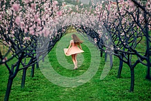 Woman enjoying spring in the green field with blooming trees