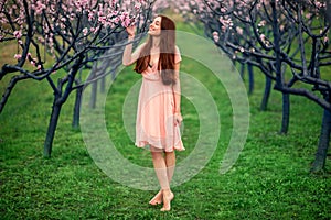 Woman enjoying spring in the green field with blooming trees