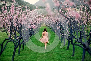 Woman enjoying spring in the green field with blooming trees