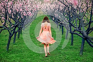 Woman enjoying spring in the green field with blooming trees
