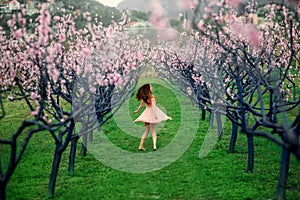 Woman enjoying spring in the green field with blooming trees