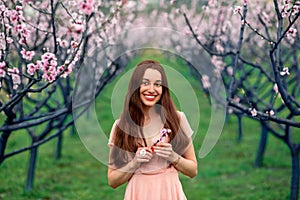 Woman enjoying spring in the green field with blooming trees