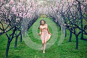 Woman enjoying spring in the green field with blooming trees