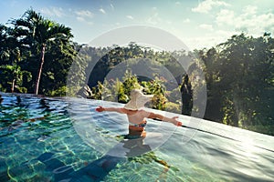 woman enjoying the sun at infinity summer swimming pool at luxurious resort