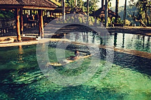 woman enjoying the sun at infinity summer swimming pool at luxurious resort and spa hotel