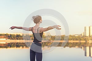 Woman enjoying sunset with arms outspread and face raised in sky photo