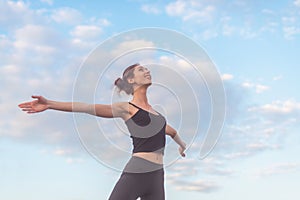 Woman enjoying sunset with arms outspread and face raised in sky photo
