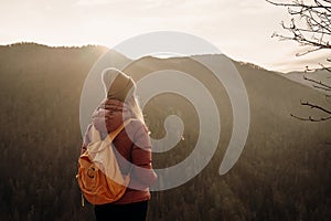 Woman enjoying the sunset in nature on the edge of a rock cliff. Woman hiker enjoys mountains view.