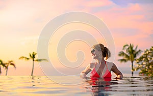 Woman enjoying sunset while relaxing in infinity pool