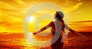 Woman enjoying Sunset. Women Rear View Silhouette Arms Outstretched looking away at Sea, Sun. Spiritual Relaxation and Meditation