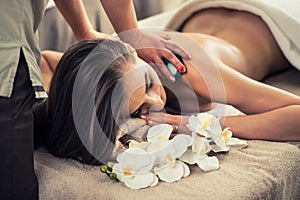 Woman enjoying the therapeutic effects of a traditional hot stone massage photo