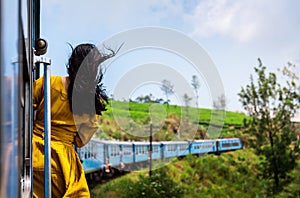 Woman enjoying train ride through Sri Lanka tea plantations photo