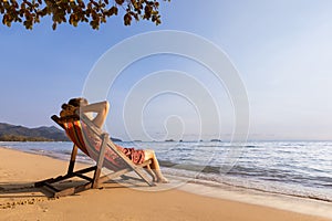 Woman enjoying vacation holidays on the beach and relaxing in a deckchair near the sea, warm sunny summer day for resting and