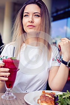 woman enjoying a vibrant red berry smoothie at a cafee