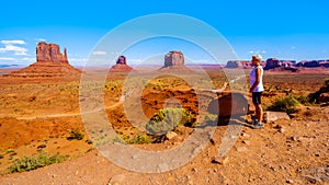 Woman enjoying the view of the sandstone formations of Mitten Buttes and Merrick Butte in Monument Valley