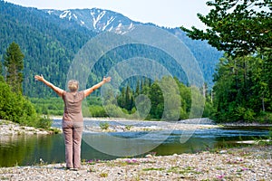Woman enjoying the views of the Snezhnaya Snowy river, forest and mountains