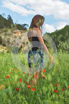 Woman enjoying a walk in a poppy field under the summer sun.