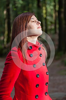 Woman enjoying the warmth of the winter sunlight on a forest