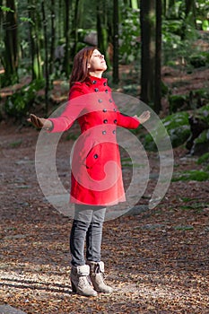 Woman enjoying the warmth of the winter sunlight on a forest