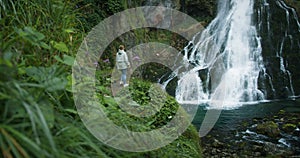 Woman enjoying waterfall in the highlands of Austria. Traveling in the mountains, adventure and trip concept.