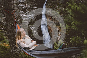 Woman enjoying waterfall view lying in hammock in forest travel lifestyle outdoor with camping gear