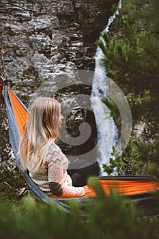 Woman enjoying waterfall view relaxing in hammock travel lifestyle in Norway adventure vacations