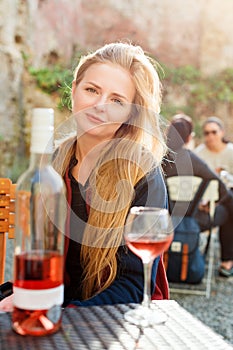 Woman enjoying wine in outdoor restaurant. Portrait of a beautiful wine tasting tourist girl.