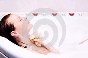 Woman enjoys the bath-foam in the bathtub.