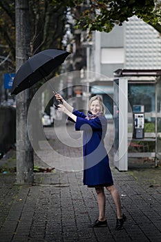 A woman enjoys opening an umbrella on the street.