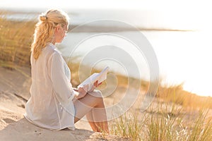 Woman enjoys reading on beautiful sandy beach.