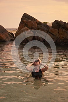 Woman enjoys serene sea swim at sunset. Wellness, mindfulness in natural setting. Female bather in ocean, tranquility