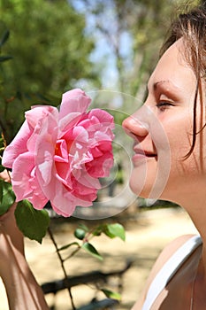 Woman enjoys a smell of a pink rose