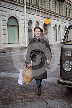 Woman enjoys a successful shopping, walking down the street with bags in her hands