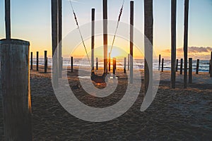 Woman enjoys the sunset by the beach on a swing