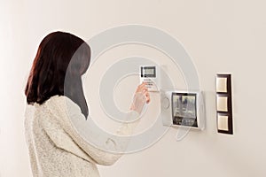 Woman entering code on keypad of home security alarm