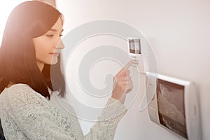 Woman entering code on keypad of home security alarm