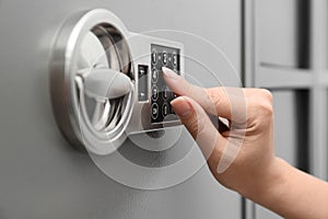 Woman entering code on keypad of safe, closeup