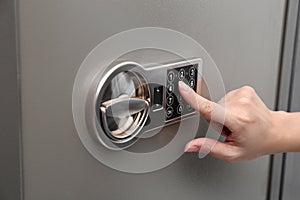 Woman entering code on keypad of safe, closeup