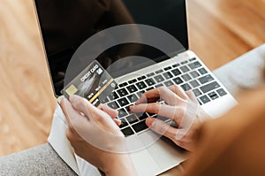 Woman entering code on laptop computer and paying bill with credit card on desk at home office, digital marketing, shopping online