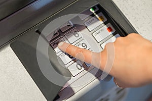 Woman entering her pin code number to atm machine.