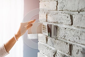 Woman entering password on home alarm keypad.