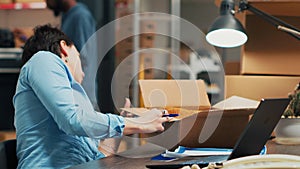Woman entrepreneur looking at merchandise in boxes to plan products shipment