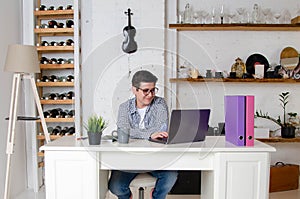Woman entrepreneur with short black hair with glasses works on laptop in stylish interior of office