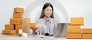 Woman entrepreneur working at home receive orders from online customers and check data while preparing to pack products deliver