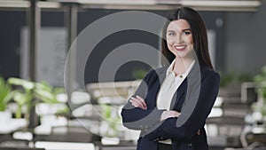 Woman entrepreneur. Young confident business lady posing with folded arms at office and smiling to camera empty space