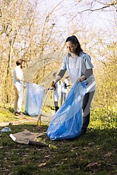 Woman environmentalist collecting junk from the ground to combat pollution photo