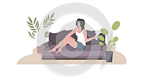 Woman epilating legs girl sitting on sofa using modern laser epilator hair removal skin care concept horizontal full