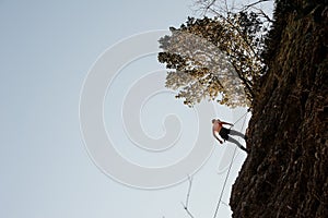 Woman equipped with a rope abseiling on the sloping rock